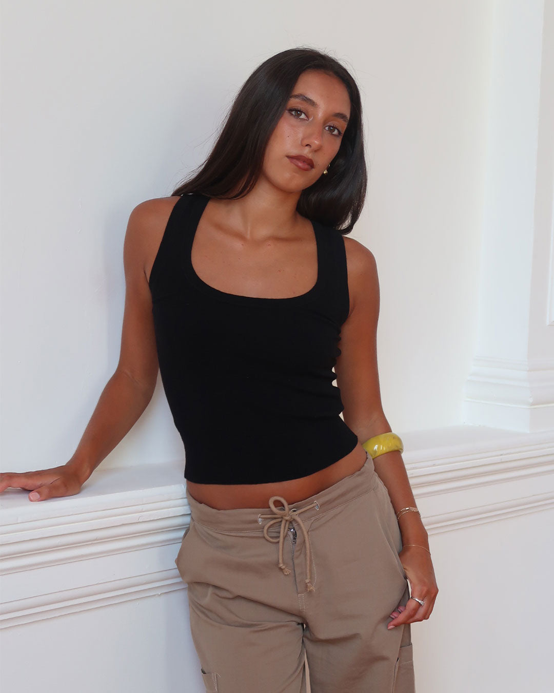 Women's black knit sleeveless top with scoop neck and cinched ribbed waist band