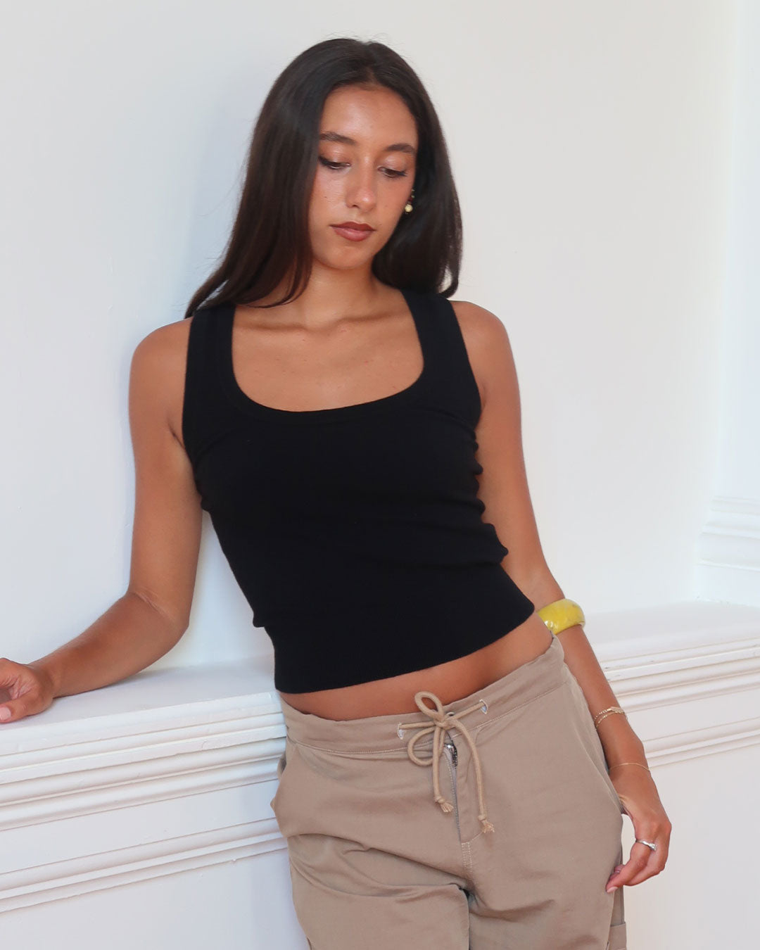 Women's black knit sleeveless top with scoop neck and cinched ribbed waist band