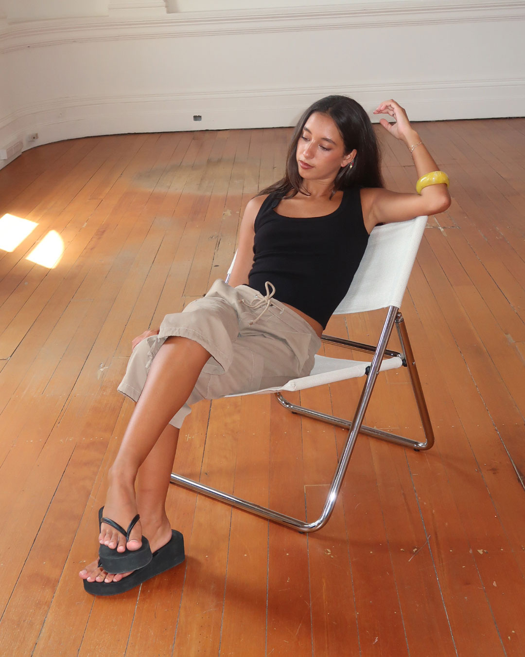 Women's black knit sleeveless top with scoop neck and cinched ribbed waist band