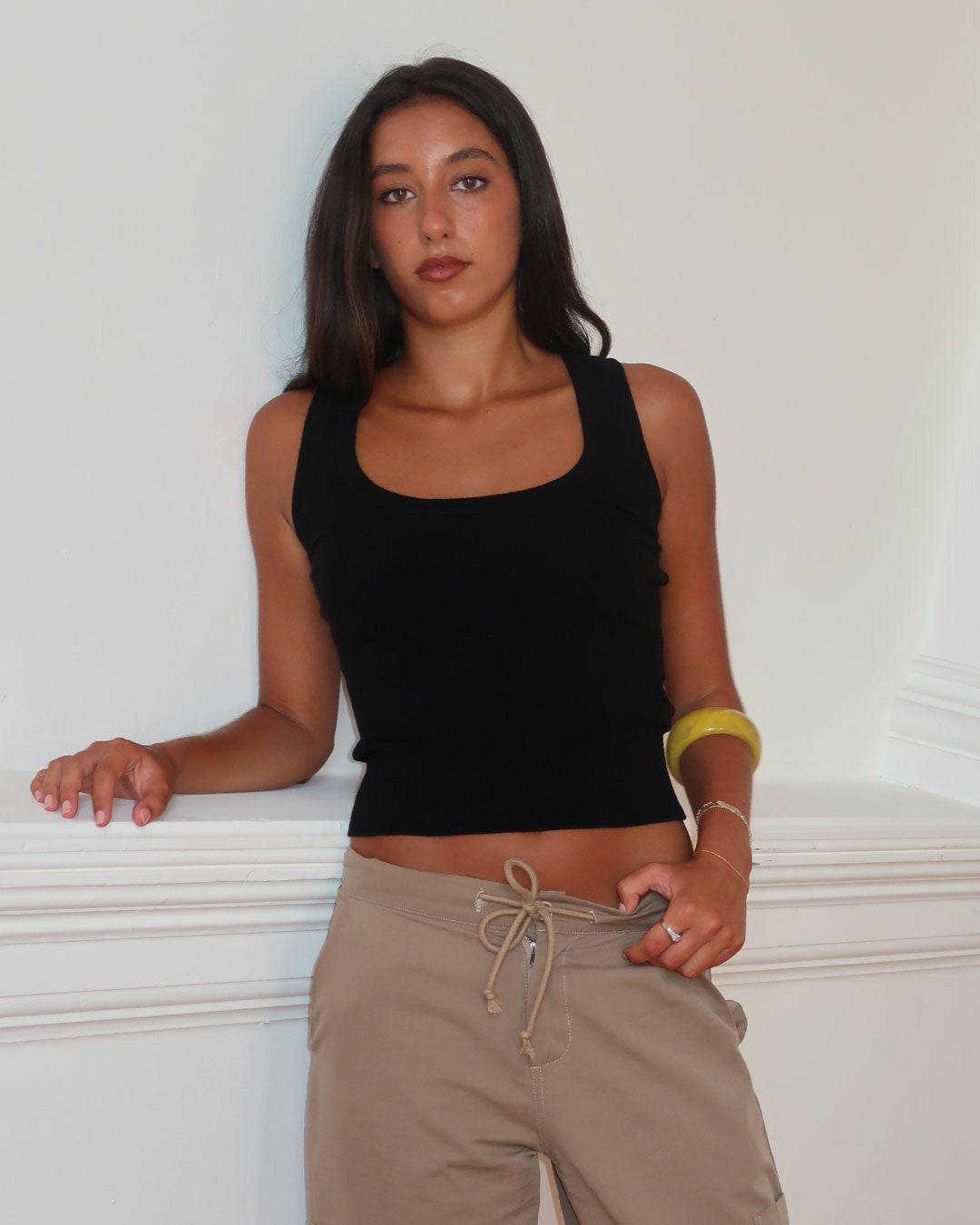 Women's black knit sleeveless top with scoop neck and cinched ribbed waist band