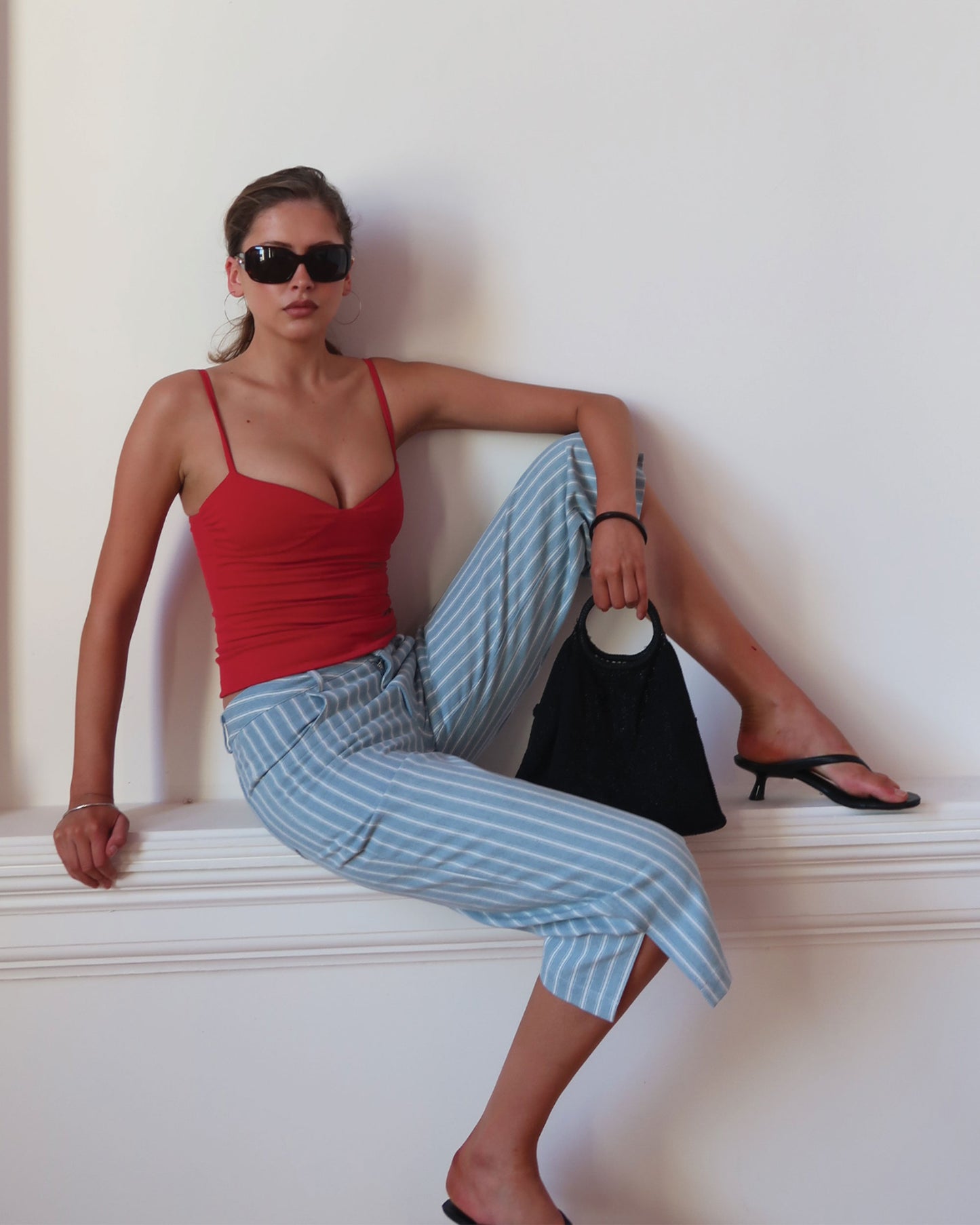 Women's singlet top in deep red colour featuring figure-hugging fit, contoured waist, and bust gathering.